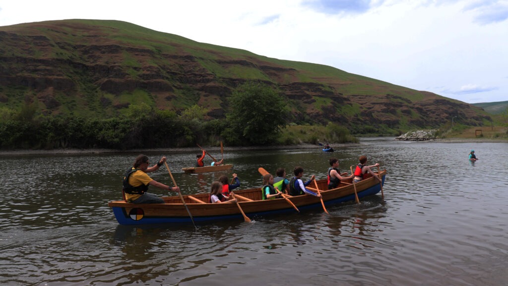Fourth-graders sit in a David-Thompson style canoe that was built by a previous class