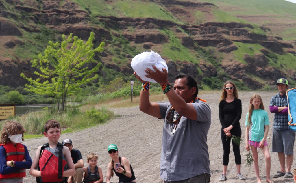 Gary Dorr raises a bundle filled with prayer ties and rocks to the sky during a ceremony