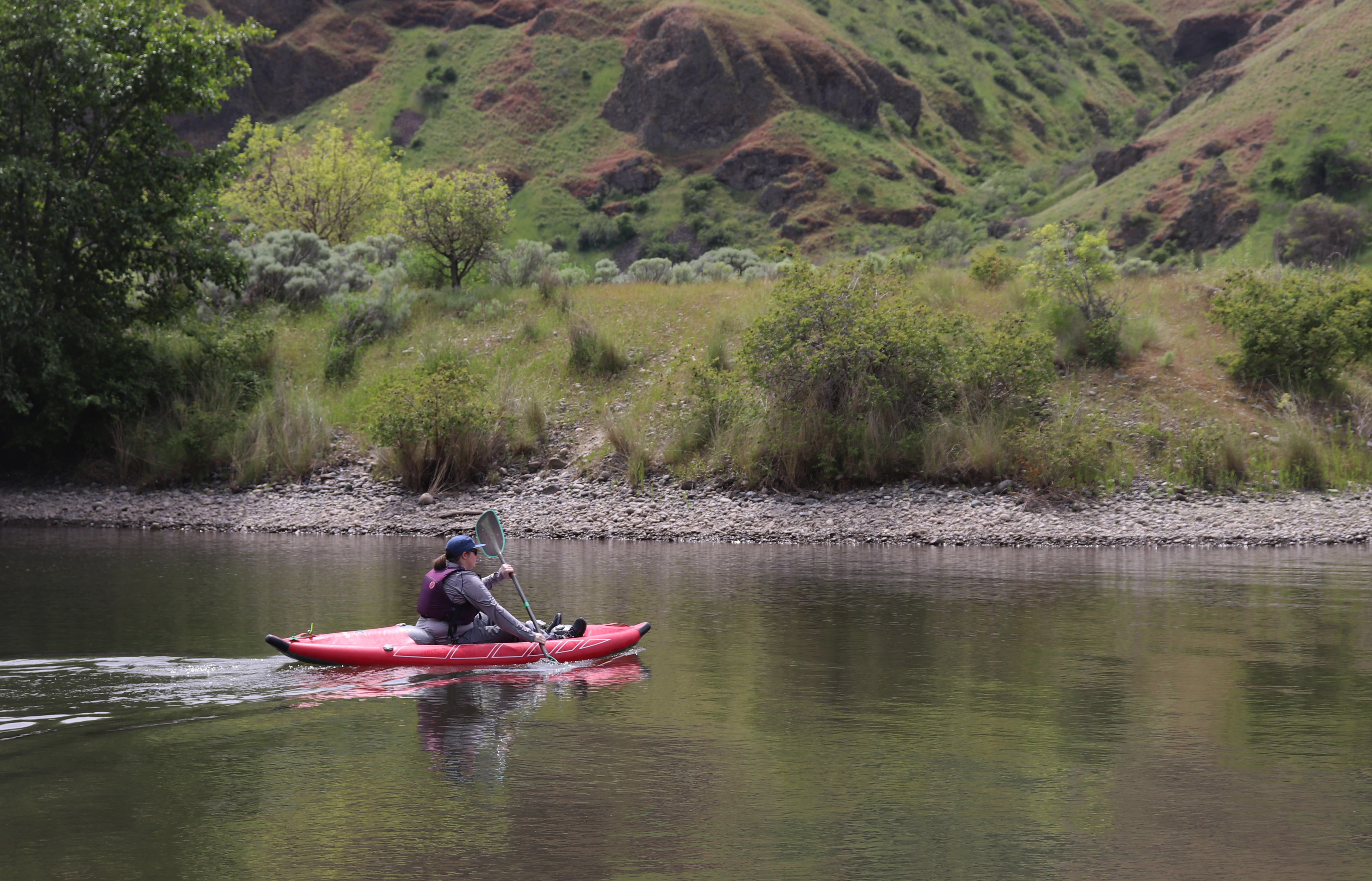 A kayaker from Northwest River Supply rows to the water’s depths to drop the bundle of prayer ties into the water