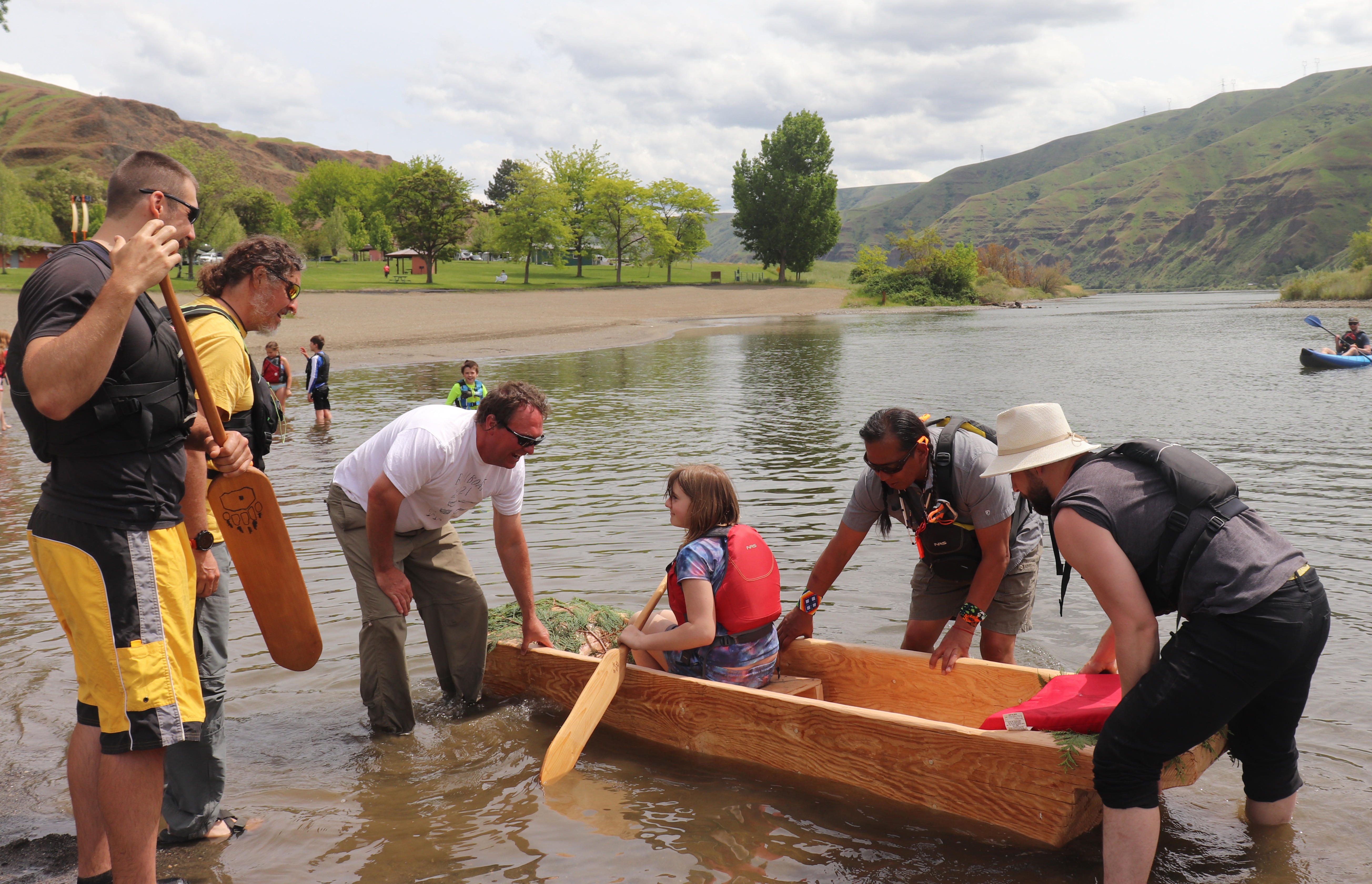 Fourth-grader Josie Tate sits in the dugout canoe as Gary Dorr, Dave Paul and other volunteers push the canoe into the water