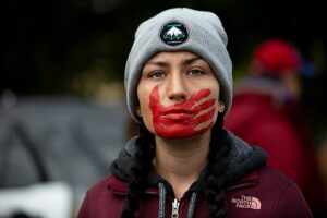 A participant in the Greater Than Fear Rally & March in Rochester Minnesota. The red handprint is a symbol for missing and murdered Indigenous women and people.