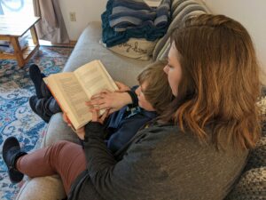 A mother holds her son while reading a story.