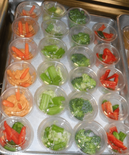 Color coordinated cups of carrots, broccoli and red peppers for school lunches