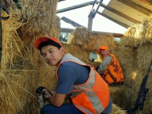 Ethan Duong, 16 of Airway Heights, Washington, sits in a deer blind made of hay bales with his mentor Rick Brazell, president of First Hunt Foundation.