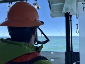 Jonathan Witmer, a NOAA survey technician, measure the angle of a net in the water.