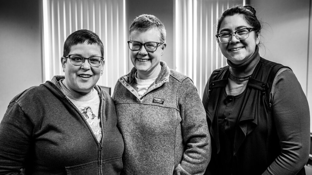 Tabitha Simmons (left), Kathy Sprague (middle), and Sueann Ramella (right) pose together, smiling for the camera.