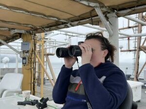 Scientist Clara Bird scans the horizon for any signs of whales.