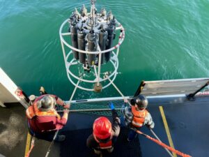 The deck crew on NOAA's Bell M. Shimada hauls the CTD machine back on deck after it collected water samples from the ocean.