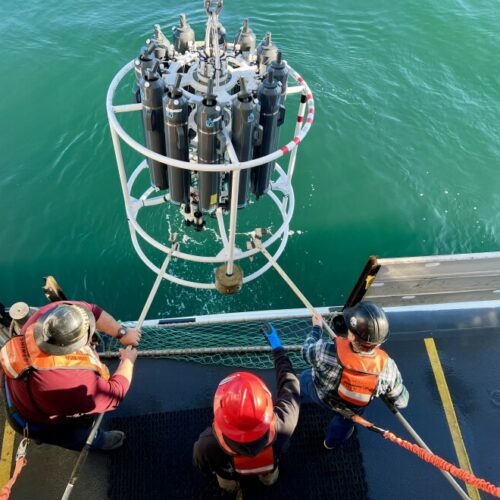 The deck crew on NOAA's Bell M. Shimada hauls the CTD machine back on deck after it collected water samples from the ocean.