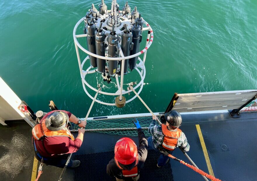 The deck crew on NOAA's Bell M. Shimada hauls the CTD machine back on deck after it collected water samples from the ocean.