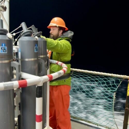 Jonathan Witmer, a survey technician with NOAA, readies equipment for the scientists as waves crash against the side of the ship