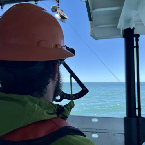 Jonathan Witmer, a NOAA survey technician, measure the angle of a net in the water