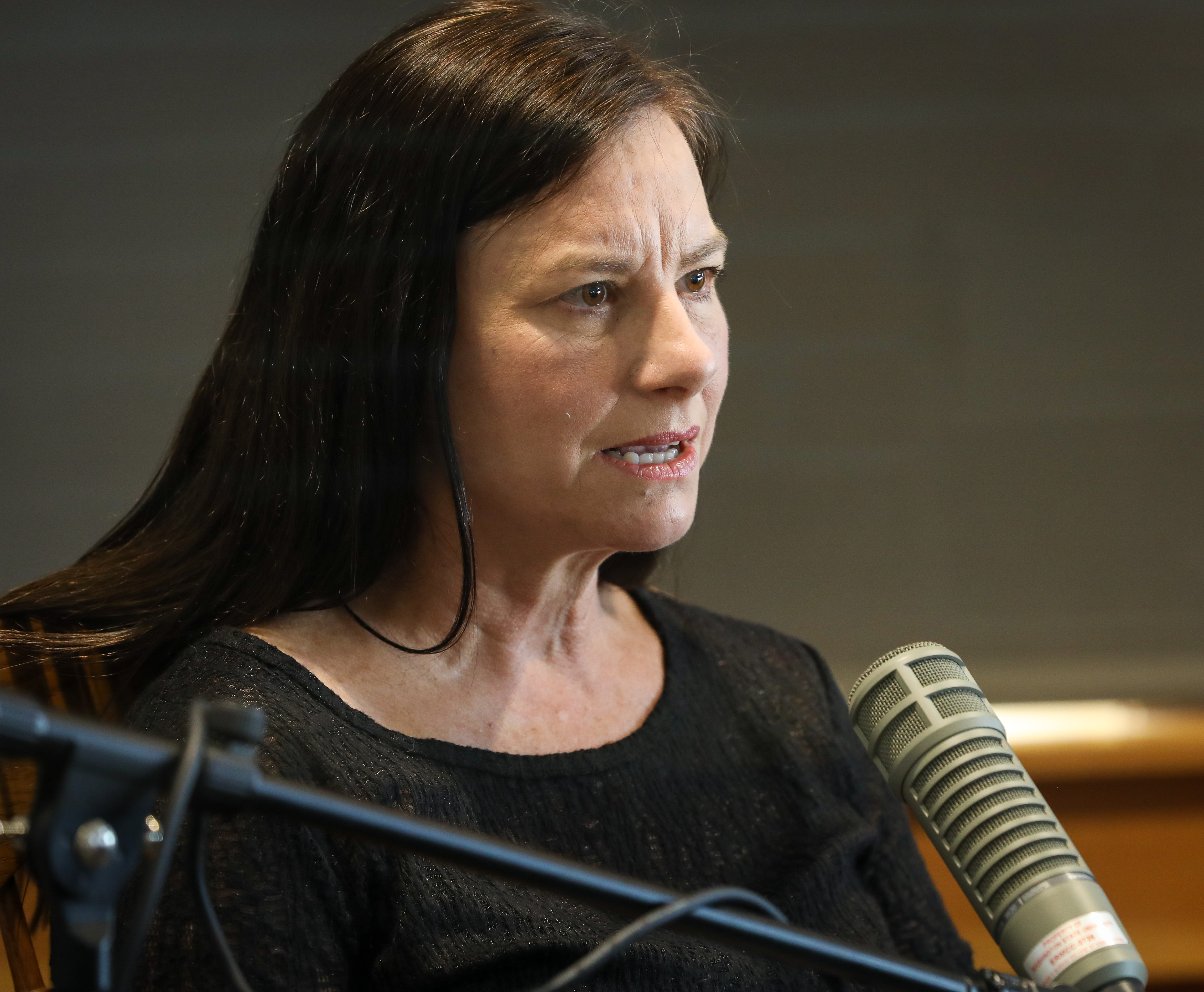 In this photo, Sarah Zabel displays a focused and serious look as she speaks into a microphone.
