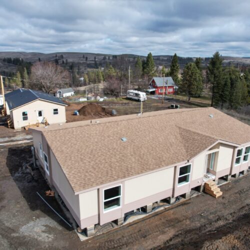 A bird's eye view shows newly constructed houses upon a brown and muddy street.