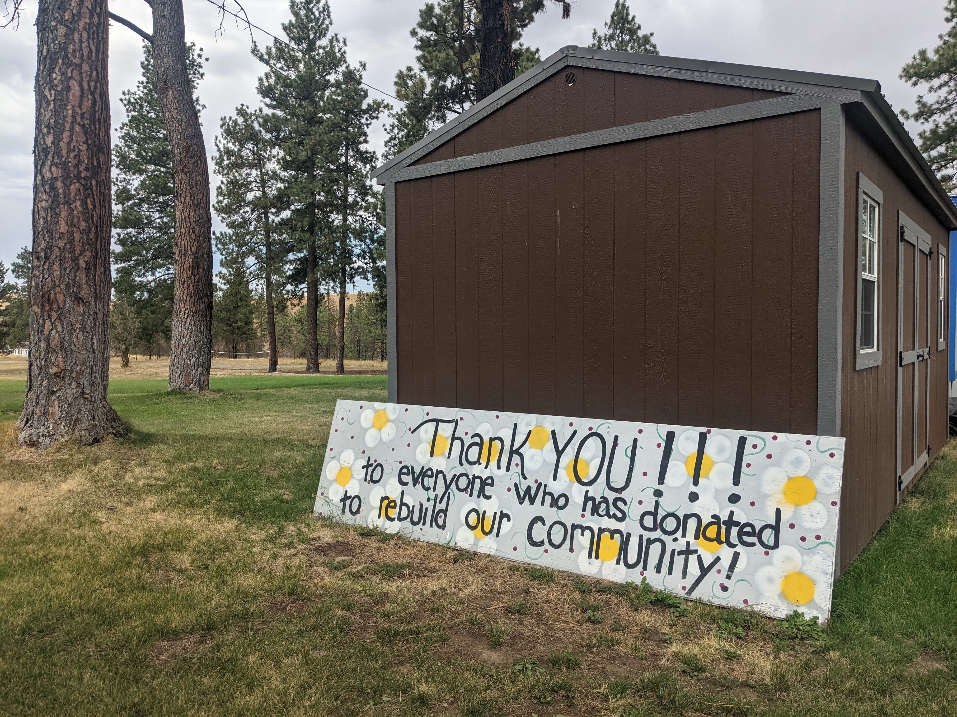A sign reading "thank you to all who donated to our community" sits beside the temporary town hall in Malden.