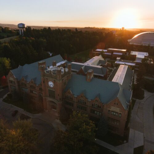 A bird's eye view shows the University of Idaho admin building and clock tower at sunset.