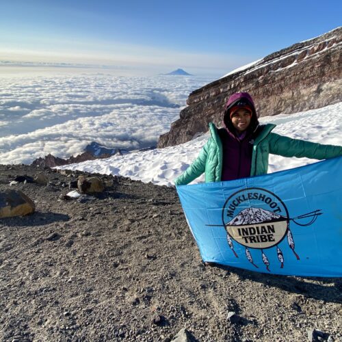 Rachel Heaton holds up the Muckleshoot Tribe flag on top of Mount Rainier. Photo courtesy of Heaton.