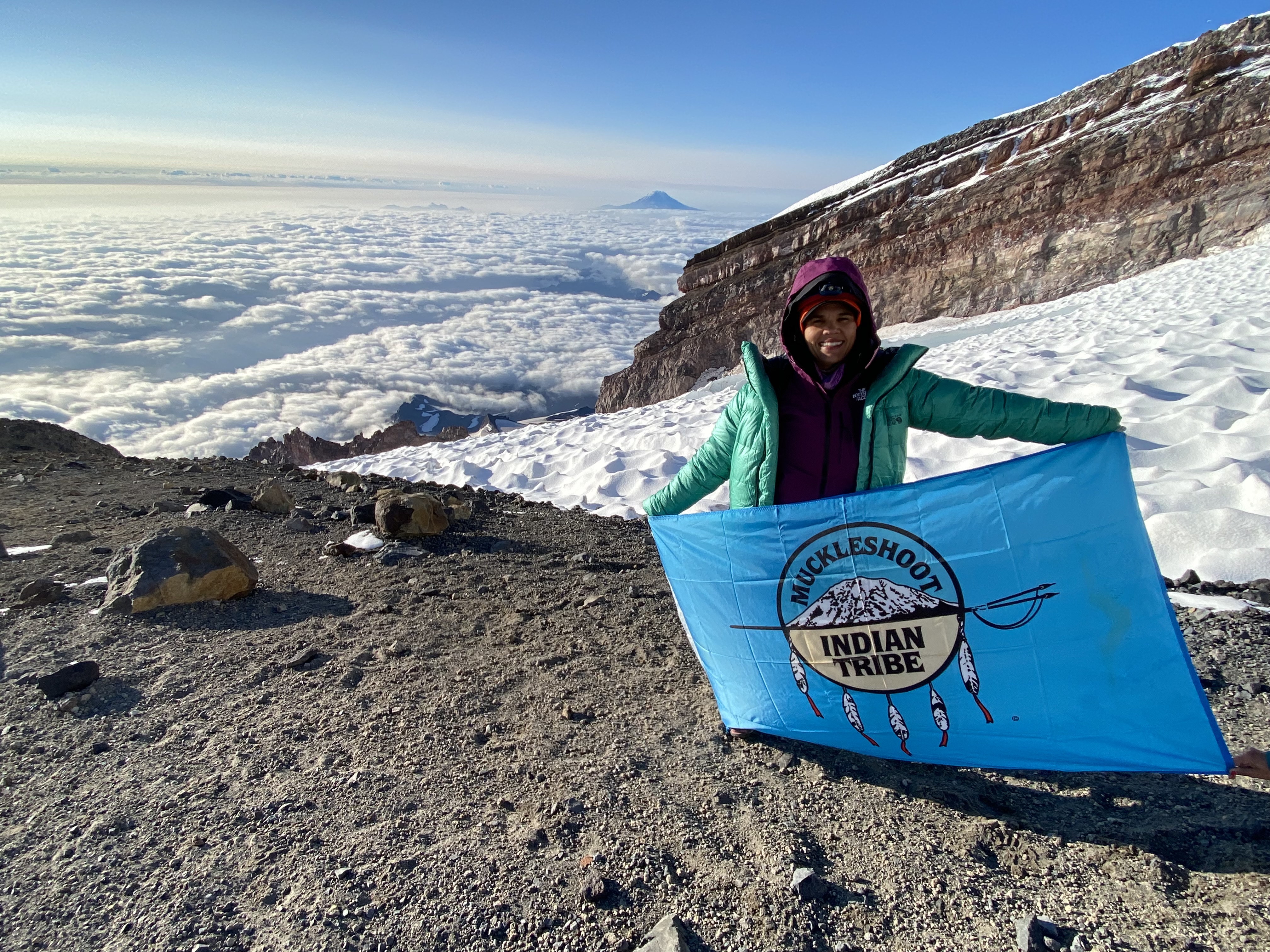 Rachel Heaton holds up the Muckleshoot Tribe flag on top of Mount Rainier. Photo courtesy of Heaton.