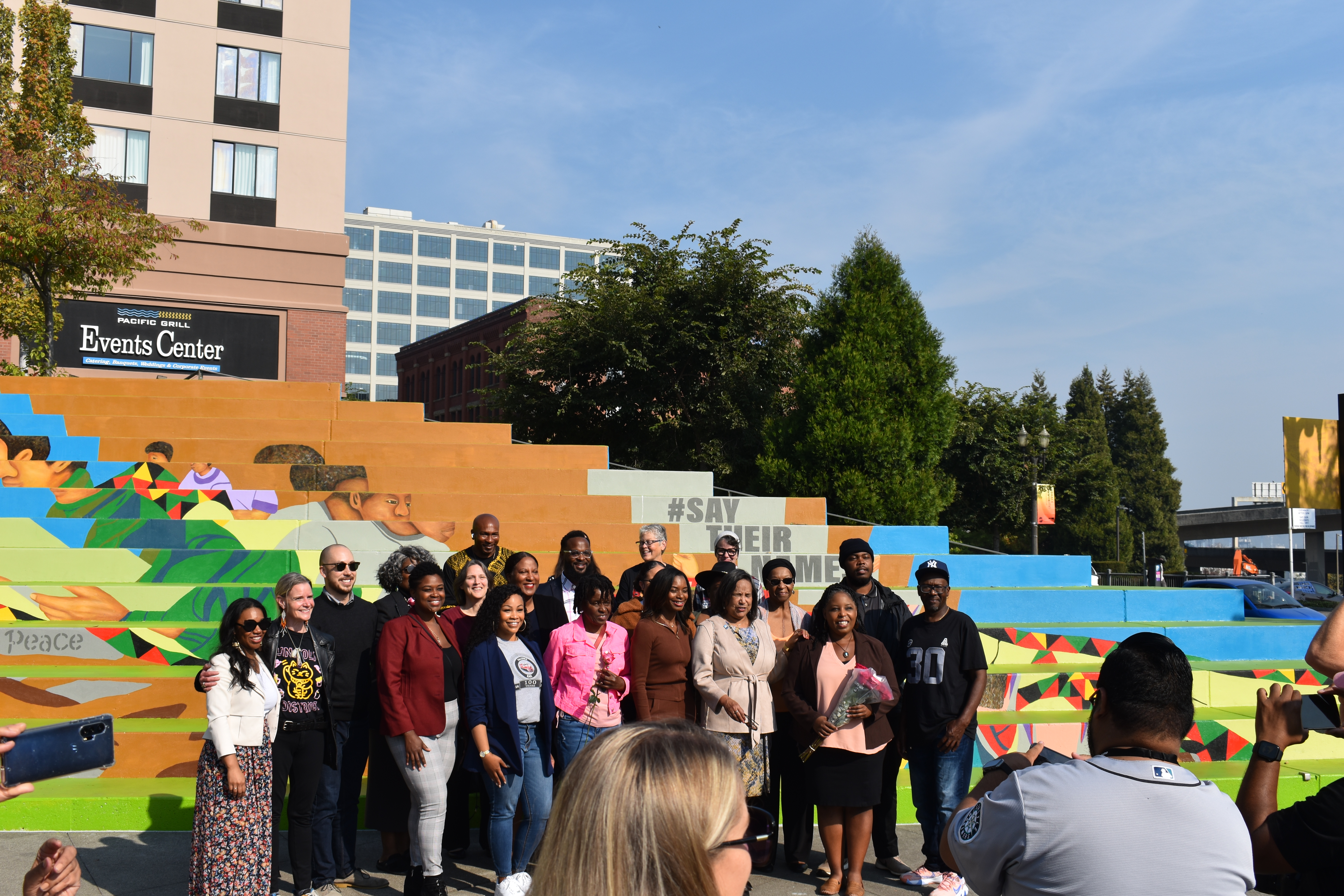 Some of the people who made Tacoma's Black Lives Matter mural come together, including lead-artist Dionne Bonner holding a bouquet of flowers, with Mayor Victoria Woodards on her right. Photo by Lauren Gallup.