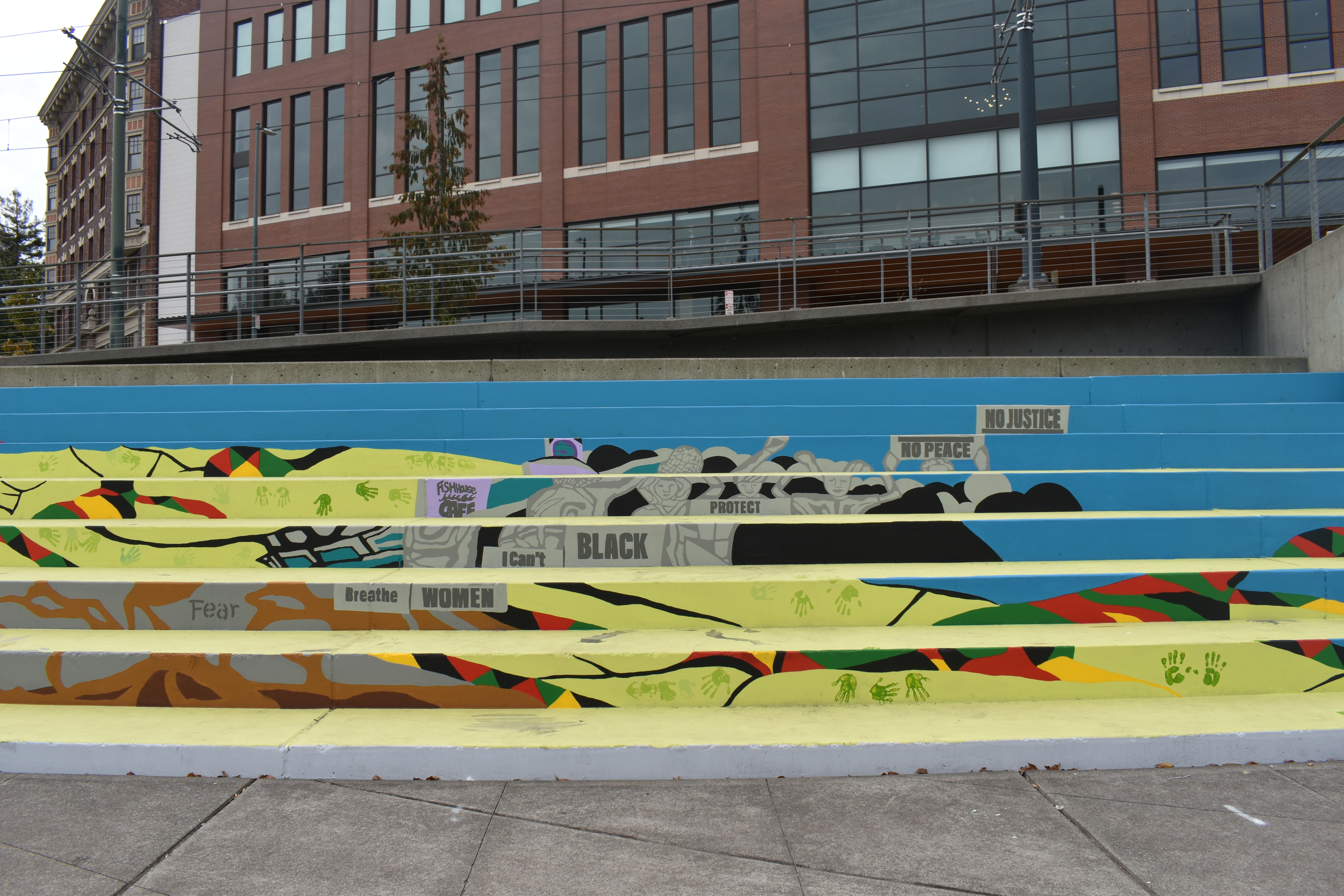 Another portion of the mural, with protest signs reading "No Justice No Peace," "Protect Black women," and "I can't breathe." Photo by Lauren Gallup.