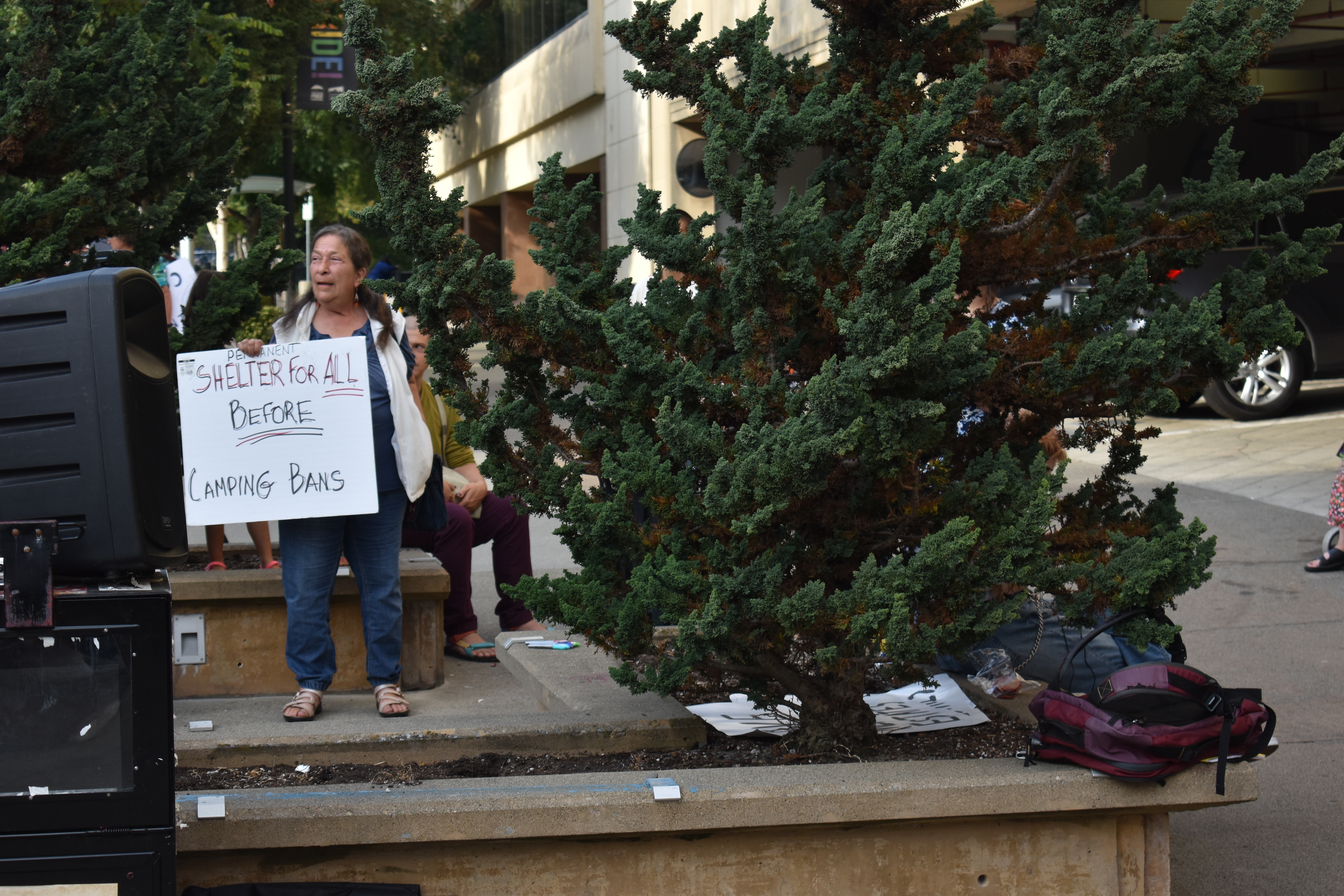 A protestor holds a sign that reads "Shelter All Before Camping Bans" at last week's Rally for Housing Justice, outside the Tacoma City Council meeting. Photo by Lauren Gallup.