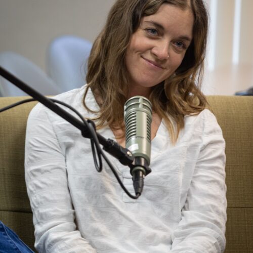 This is a photo of podcast guest Emerald LaFortune. She smiles in front of a microphone.