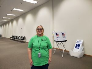woman in a green shirt standing in a voting center