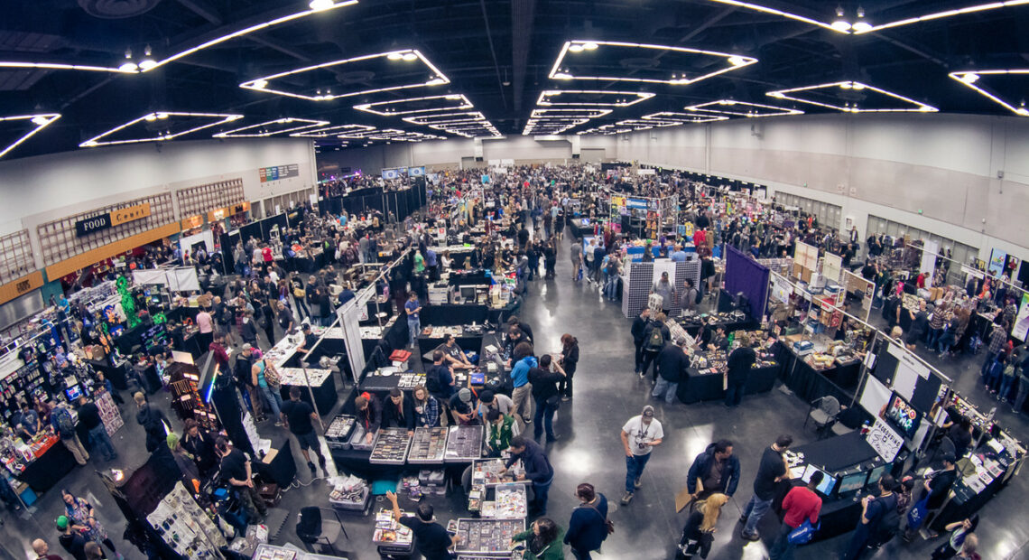 A bird's eye view shows the Oregon Convention Center filled with people and stands.