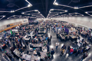 A bird's eye view shows the Oregon Convention Center filled with people and stands.