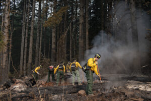 Firefighter Evan Marsh, right, tackles smoldering ground in the Camas Creek Watershed while working with colleagues to tackle the Nakia Fire on Wednesday afternoon, Oct. 19, 2022. (Amanda Cowan/The Columbian)
