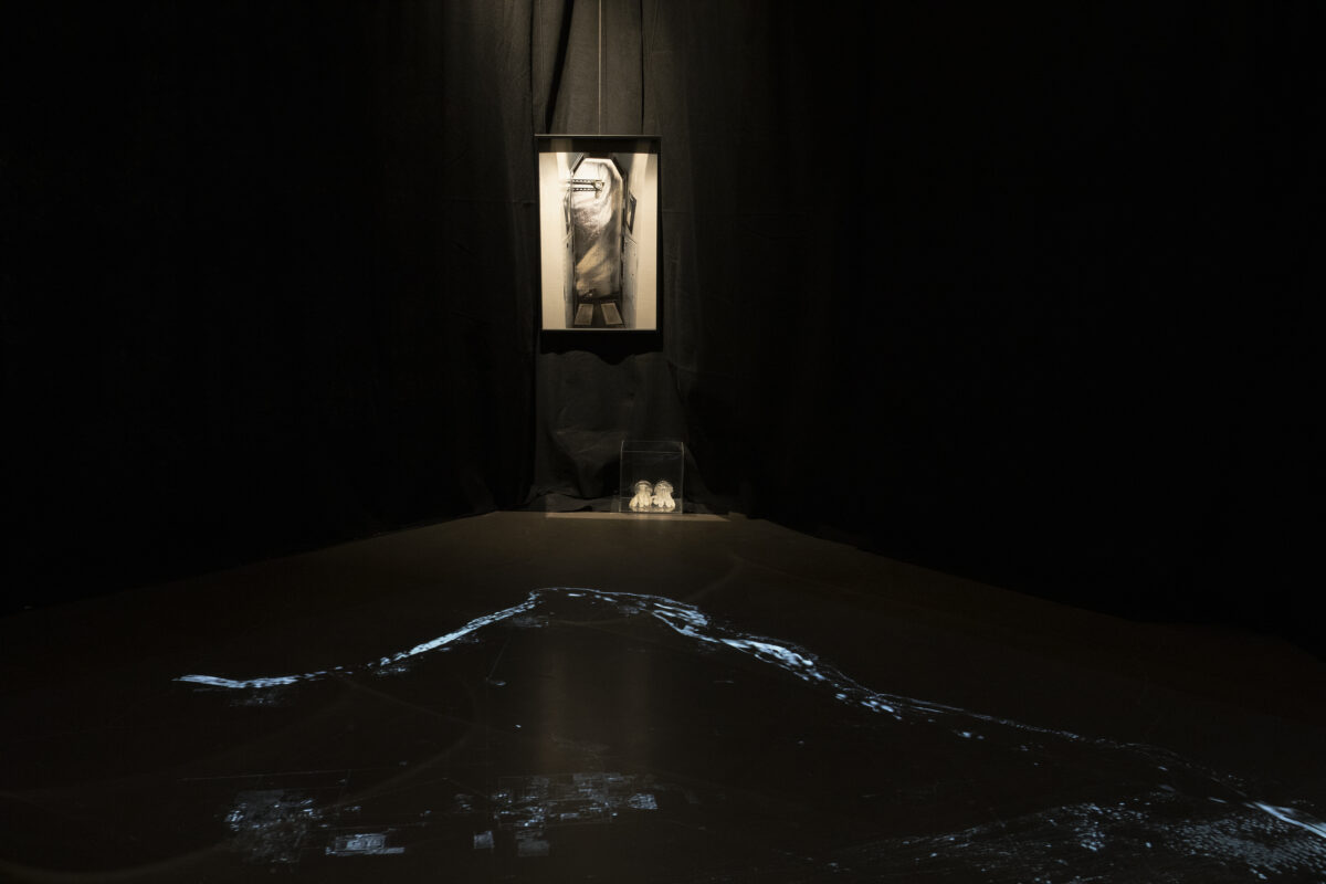 A barely visible luminescent map of the Hanford site is visible on a black table with a white portrait hanging on the wall.