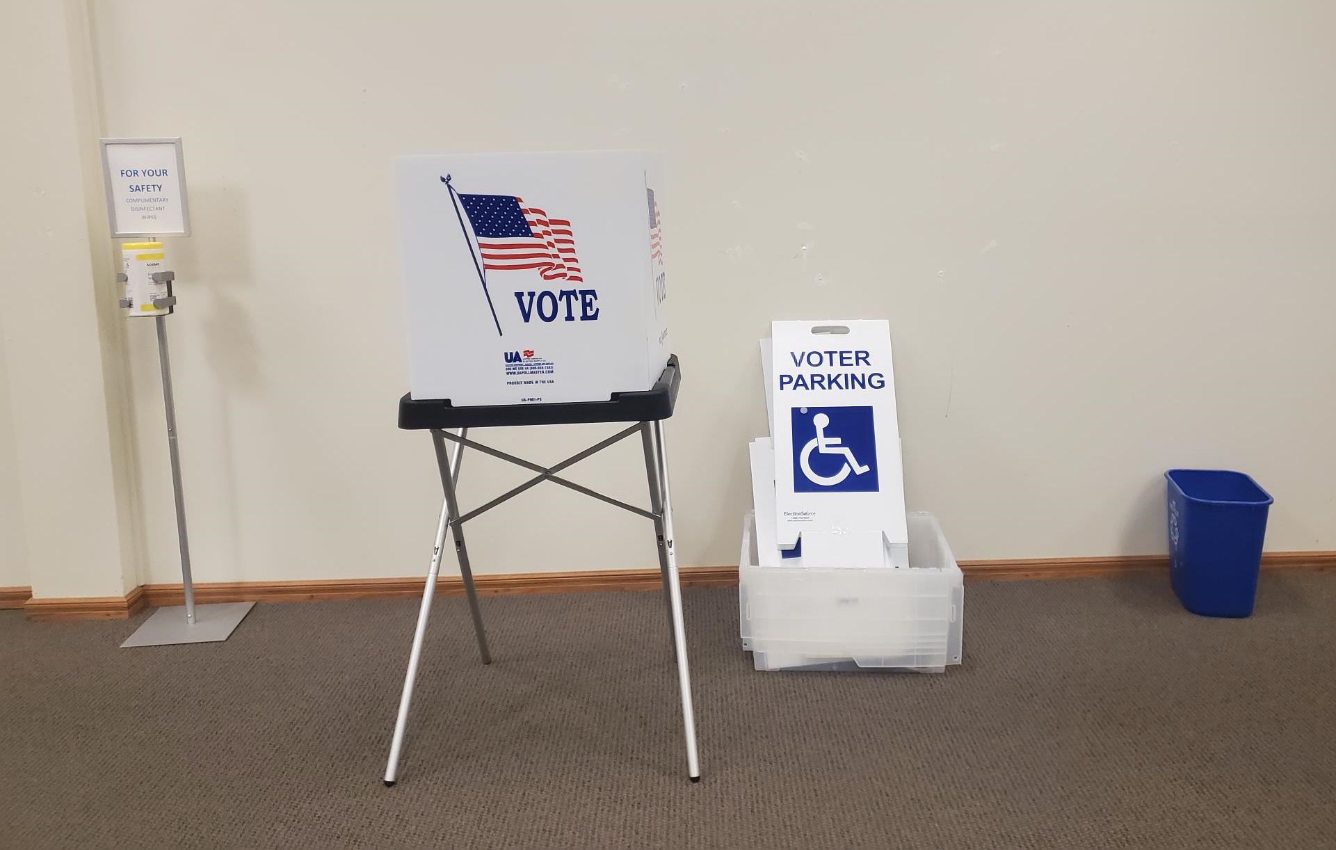 table with a voting booth, a disabled parking sign