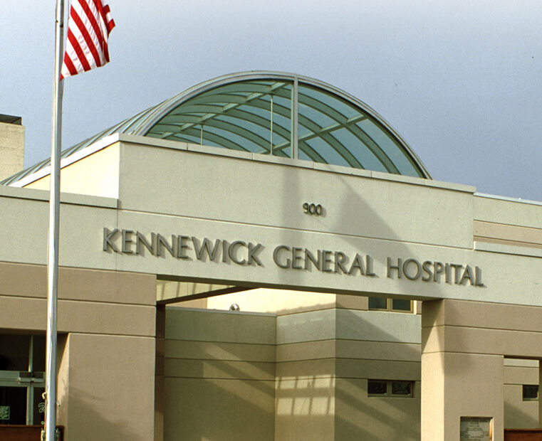 Front image of a hospital with an American flag and Washington state flag