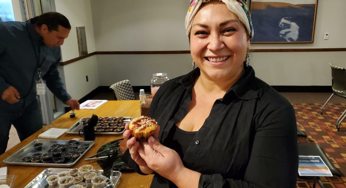 Native Woman in a colorful headscarf holds muffins on a tray