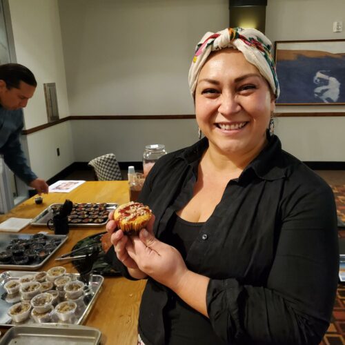 Native Woman in a colorful headscarf holds muffins on a tray