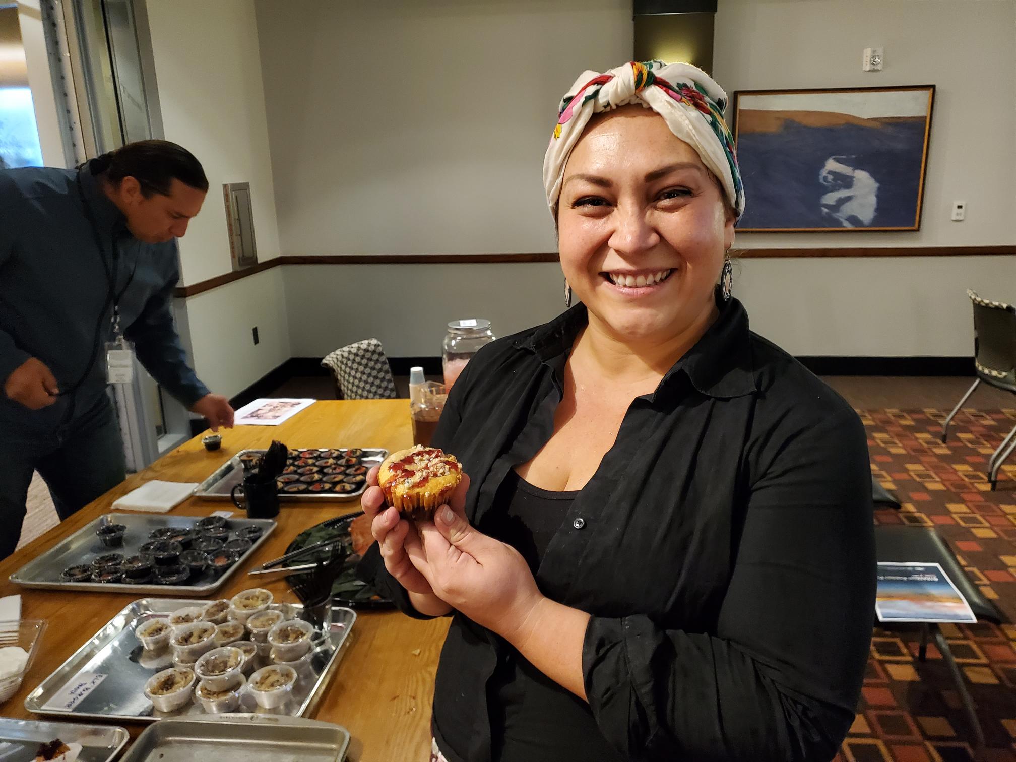 Native Woman in a colorful headscarf holds muffins on a tray