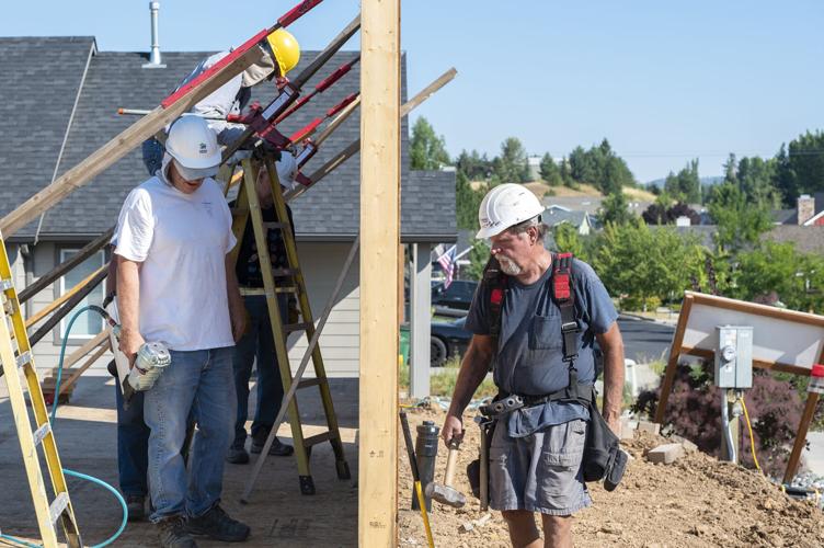 Construction worker's shown on either side of a house's just erected walls.