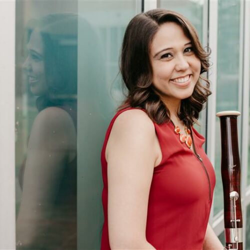 Bassoonist Dr. Jacqueline Wilson smiling with her instrument. Click here to hear the full story.