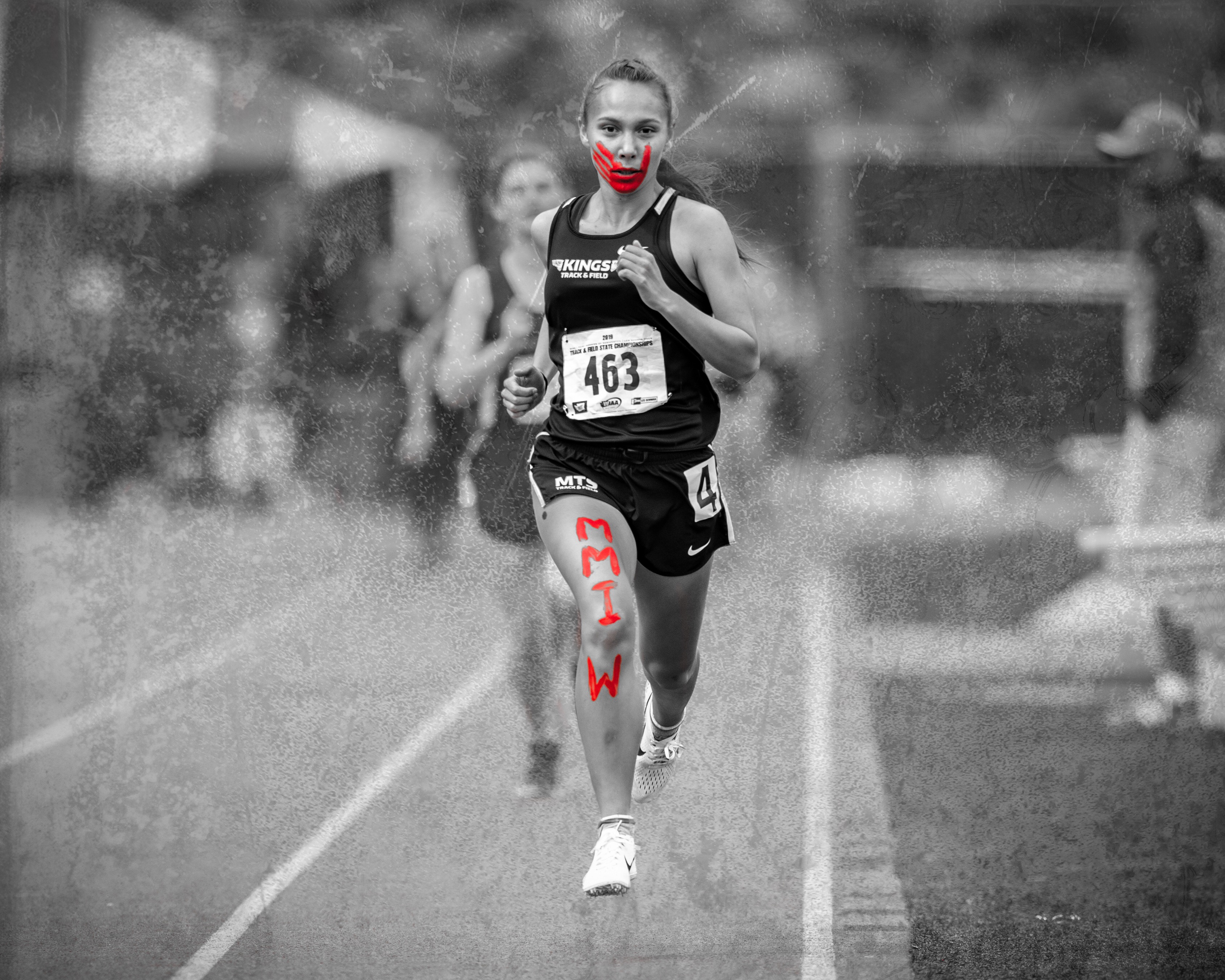 Rosalie Fish, running with a painted red handprint across her face and the letters "MMIW" along her leg to raise awareness of the Missing and Murdered Indigenous Women crisis. Photo courtesy of Fish.