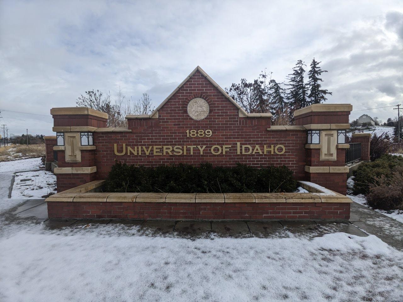 A University of Idaho sign fills the screen surrounded by brick and blue sky.