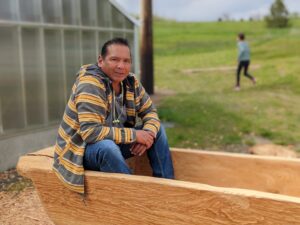 Gary Dorr sits in a canoe carved with Palouse Prairie Charter School.