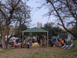 A covered place outside between two trees shelters a group of kids.