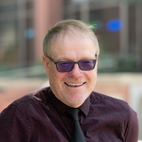 Man with sunglasses and dark shirt and tie. Steven Peterson, clinical associate professor of economics at the University of Idaho.