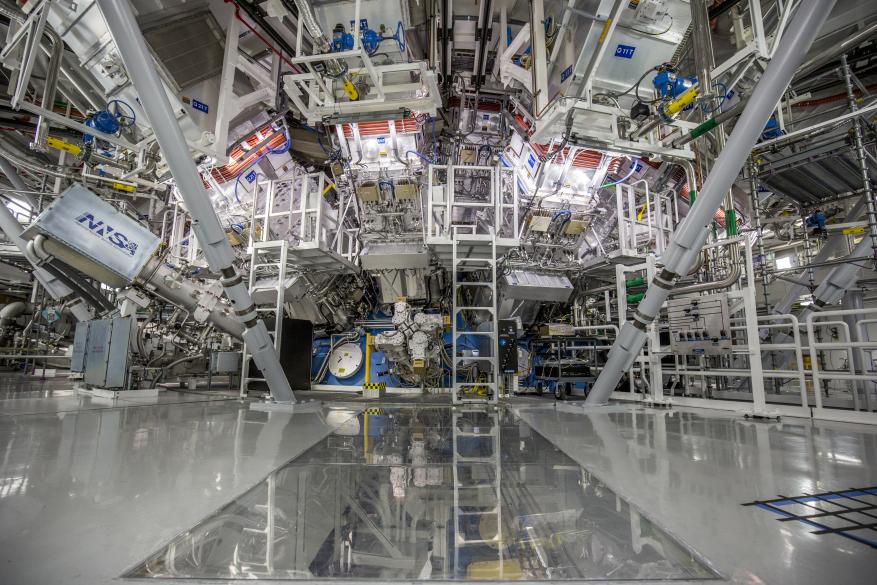 A target chamber at LLNL National Ignition facility is made up of gleaming white and gray and yellow surfaces reflecting bars of yellow and white throughout the scientific experiment space.