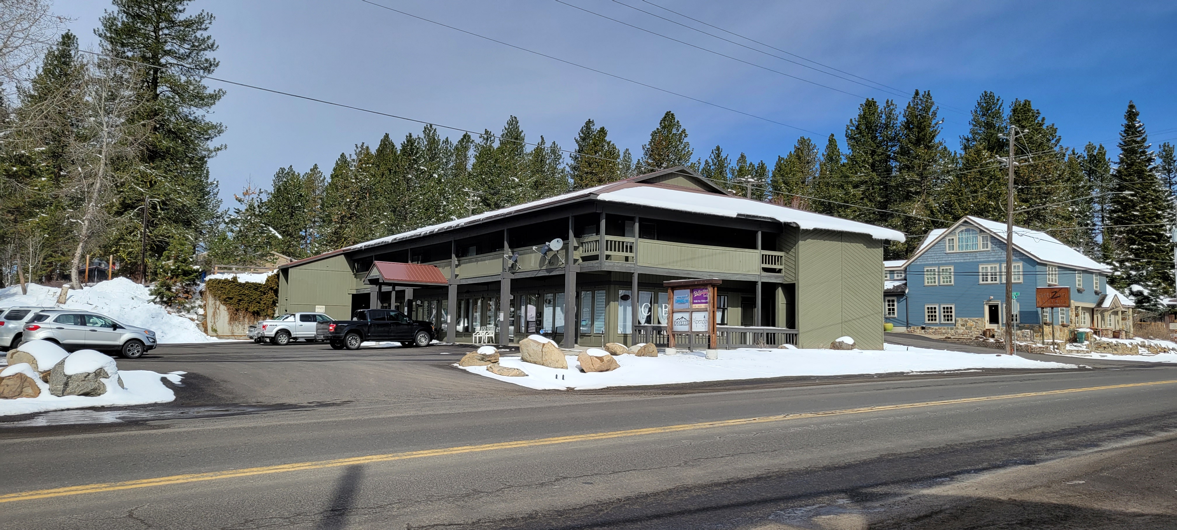 Green trees surround a green two-story building along a road in McCall, Idaho.