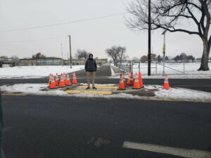 a man stands on a road island with construction cones