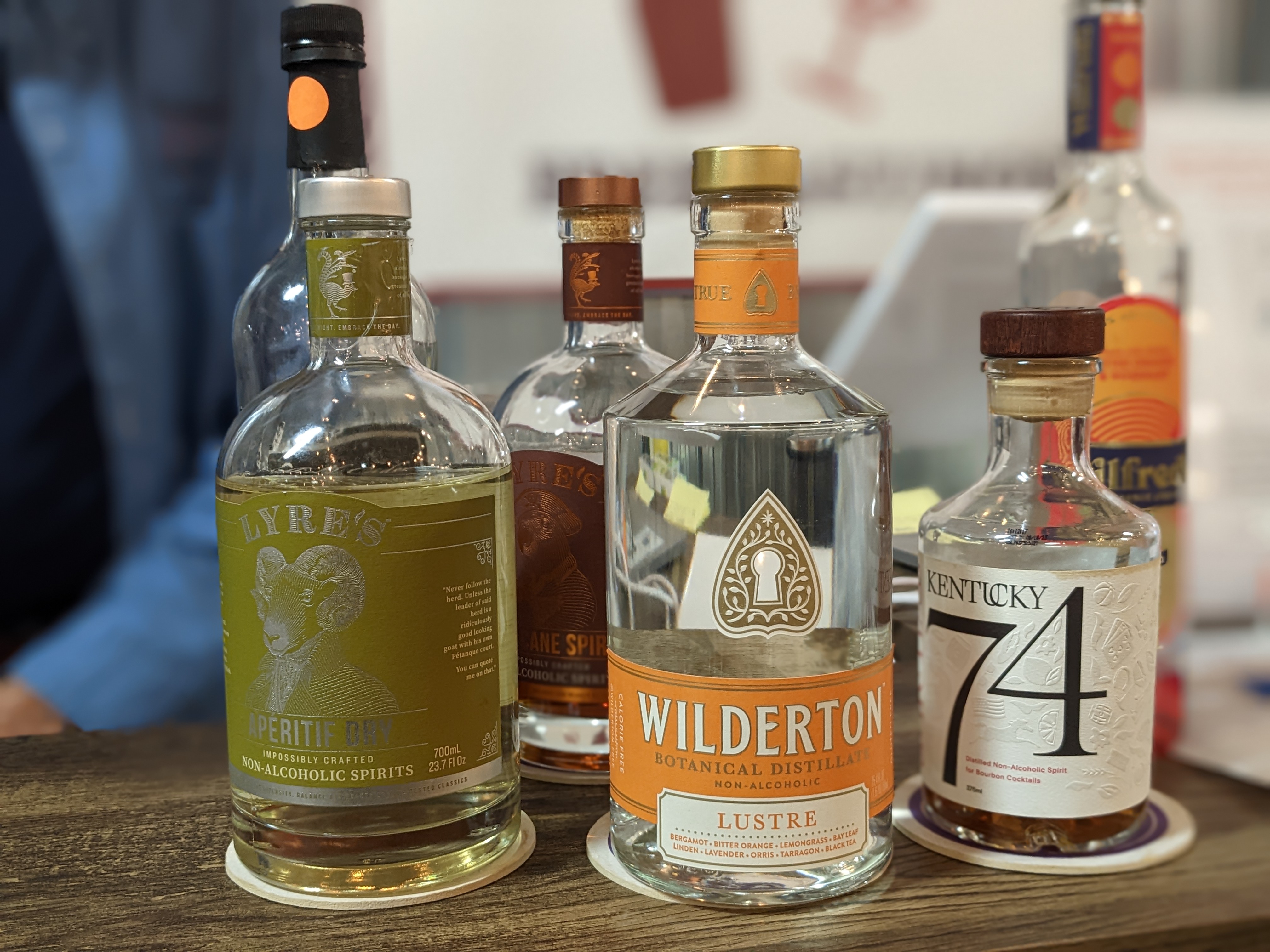 Bottles of clear liquid with white, green, and orange labels sit atop a brown countertop at the Kennewick Public Market.