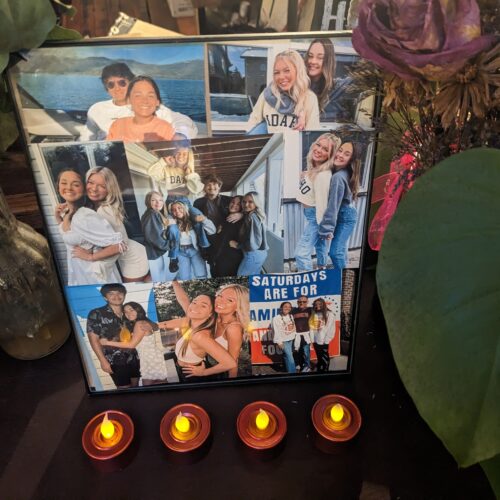 A poster shows a collage of photos of the four victims of the Moscow homicides. Four small candles sit before the poster on a dark brown table.