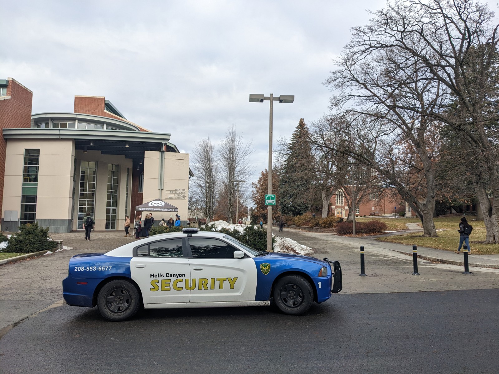 A security cruiser is parked in front of a brick building at the University of Idaho.