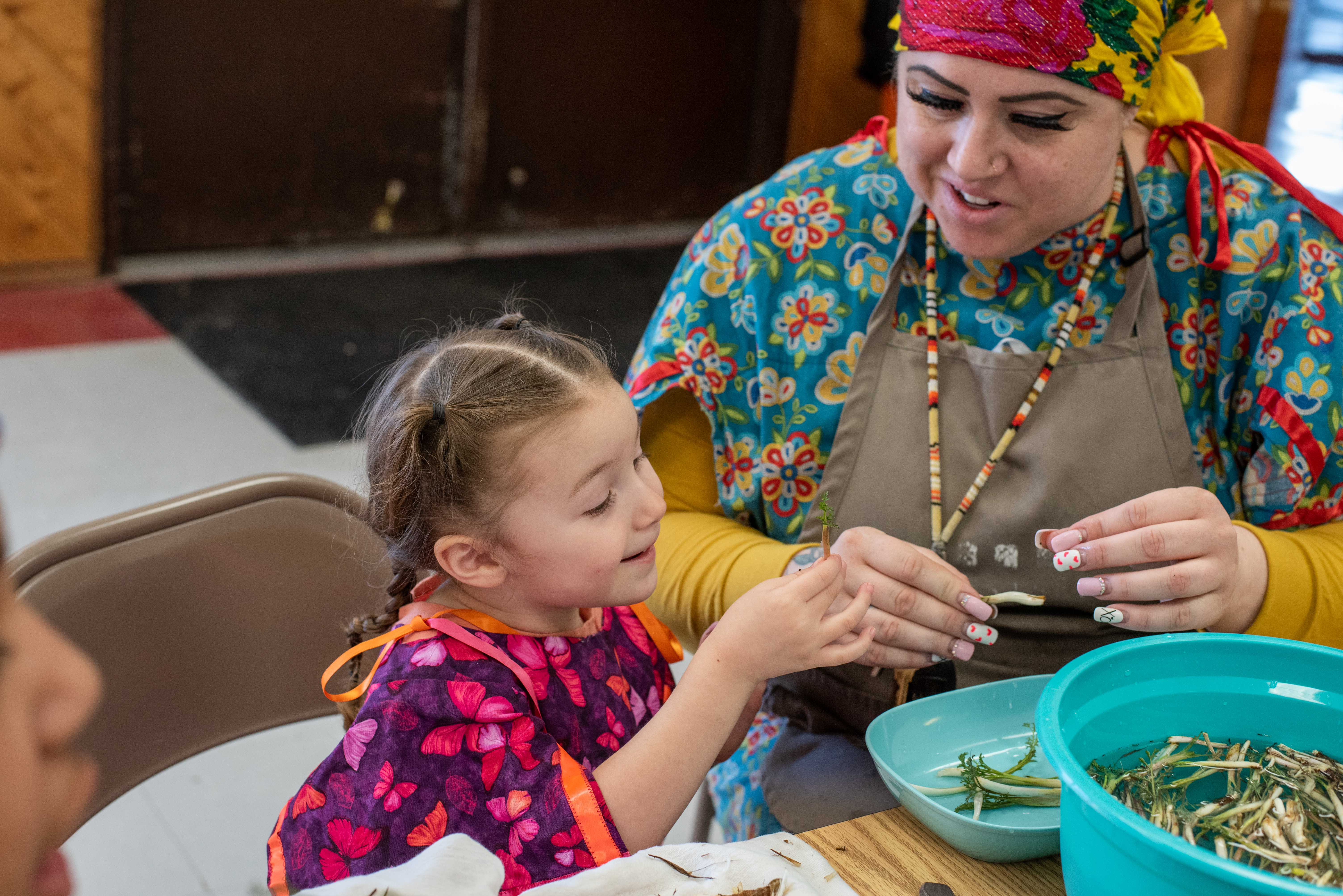 Sequoia Tias, known as Piipš, 3, sorts wild celery with her mother, Michelle Tias, in the Mission Longhouse on March 4. This marks the youngster’s first year digging for the annual celery feast. She keeps her plants separate from the rest and gives them to her grandmother, Shawna Gavin, 65, as a special honor during the ceremonial feast